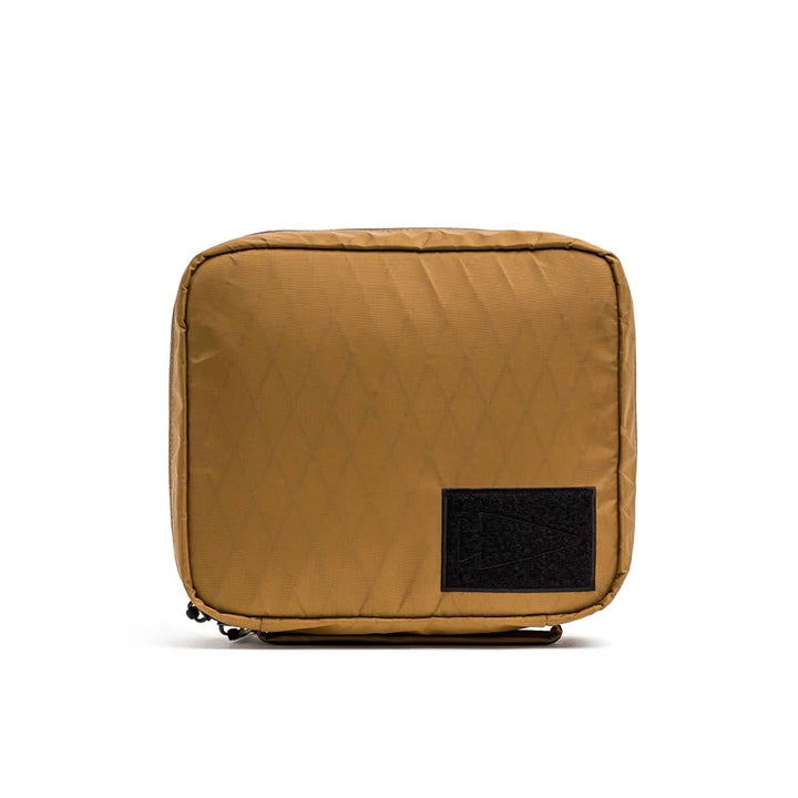 The GR2 Field Pocket - X-PAC is a square tan electronics organizer pouch with a black front patch, made from waterproof fabric, shown on a white background.