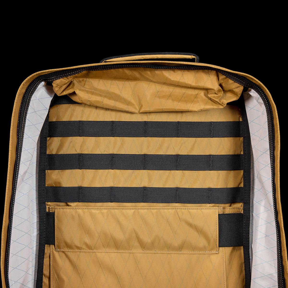 Open tan backpack showing black webbing straps and a large internal pocket against a white diamond-patterned lining.
