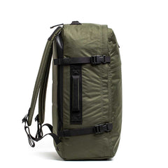 The GR3 - X-PAC carry-on backpack in olive green is shown from the side, featuring black straps, a top handle, and a waterproof construction.