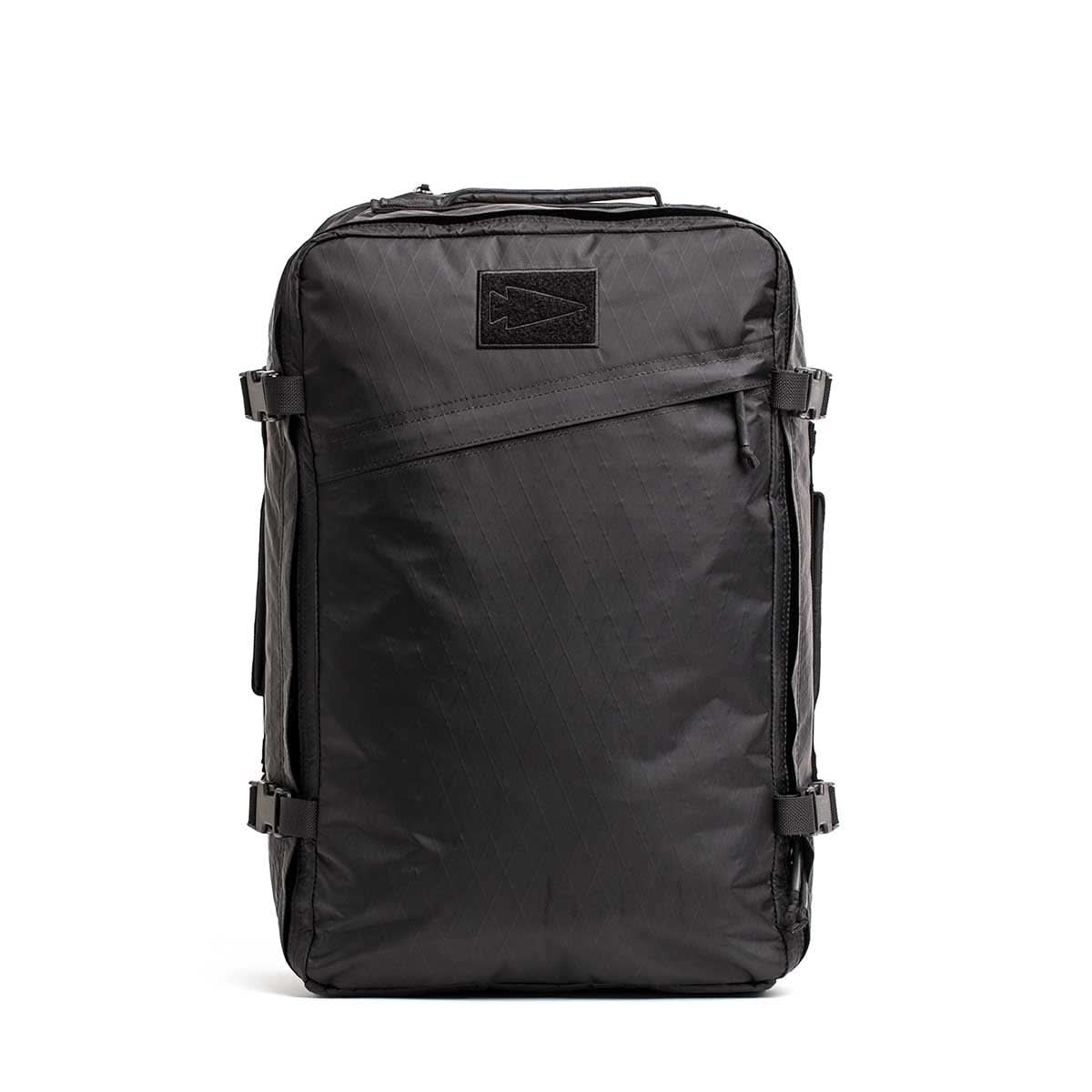 The GR3 - X-PAC is a sleek black carry-on backpack with side buckles and a diagonal front zipper pocket, made from waterproof X-Pac material for lasting durability.