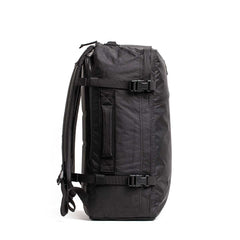 Side view of the GR3 - X-PAC, a black waterproof carry-on backpack with straps and buckles, standing upright against a white background.
