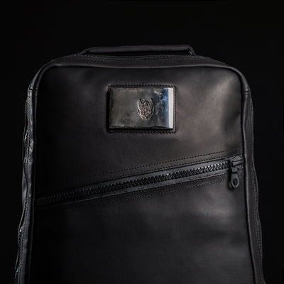 The GR1 USA x Carryology - Berserker Viking is a black leather backpack with a diagonal zipper and a metallic heart emblem patch, inspired by the resilience of Viking warriors.