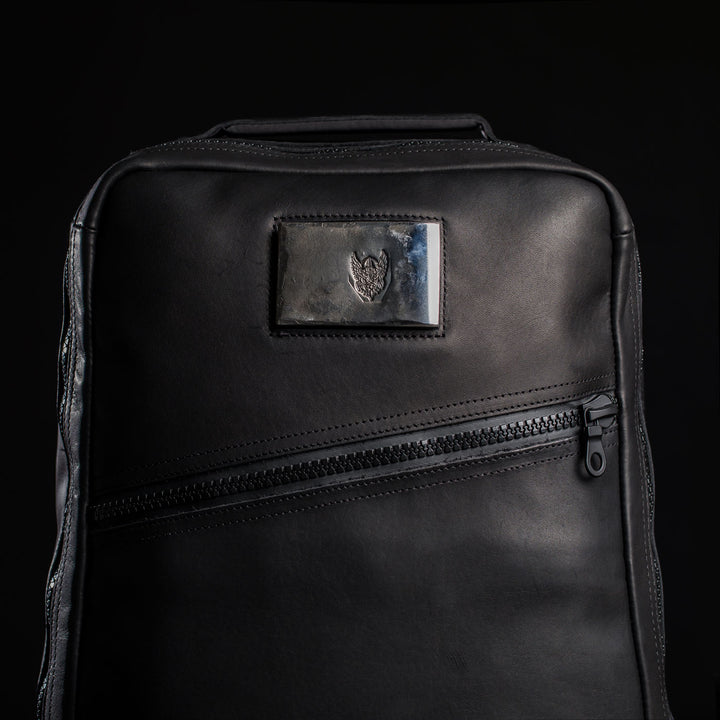 The GR1 USA x Carryology - Berserker Viking is a black leather backpack with a diagonal zipper and a metallic heart emblem patch, inspired by the resilience of Viking warriors.