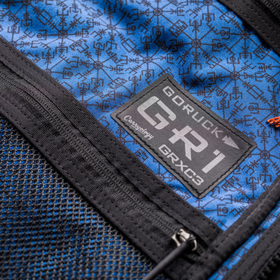 Close-up of the blue GR1 USA x Carryology - Berserker Viking backpack, highlighting its logo patch and zipper detail.