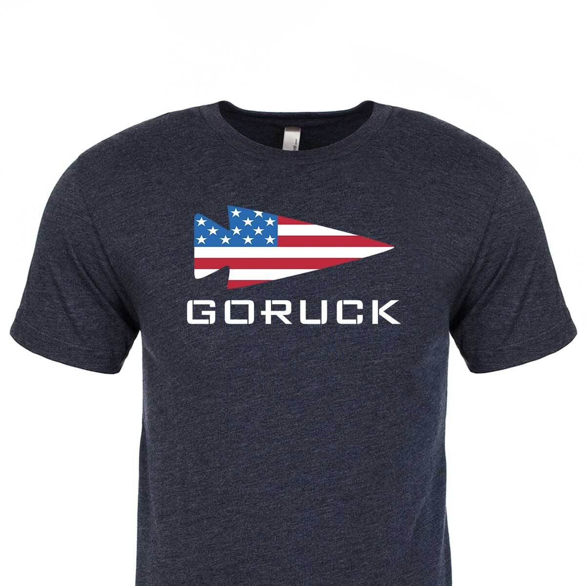 The T-shirt - GORUCK USA is a navy tee made from premium tri-blend fabric, featuring a spearhead-shaped American flag graphic above “GORUCK” in white letters.