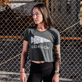 Woman wearing GORUCK grey arctic camo crop top, standing by chain-link fence outdoors