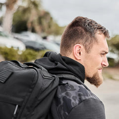 Man wearing black camouflage GORUCK Grid Fleece zipped up with black backpack outdoors