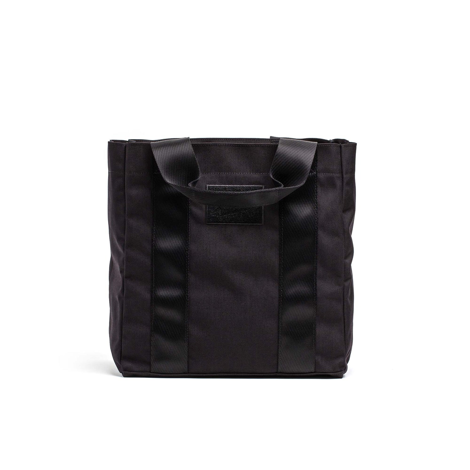Black Grocery Getter tote bag crafted from durable 1000D Cordura, featuring two handles, vertical textured stripes, and a rectangular patch on the front.