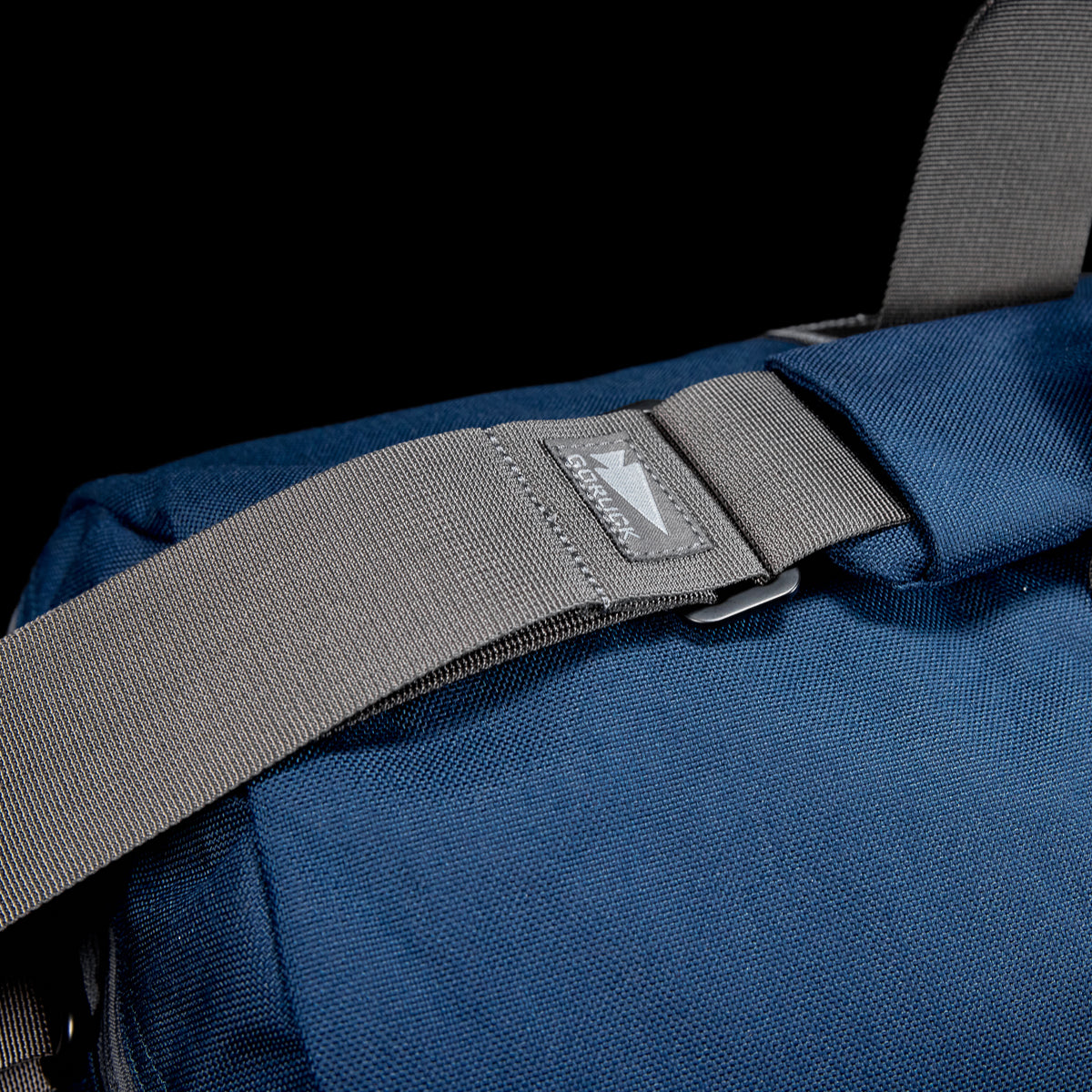 A close-up of the blue Gym Bag - Cordura with a gray strap and a small brand logo patch, crafted from durable CORDURA.