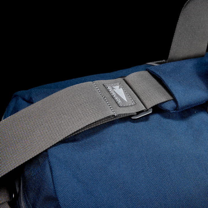 A close-up of the blue Gym Bag - Cordura with a gray strap and a small brand logo patch, crafted from durable CORDURA.