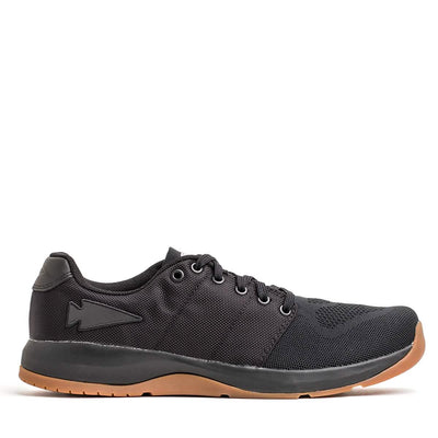 The GORUCK Men's Ballistic Trainers - HULK is a black athletic shoe ideal for functional fitness footwear enthusiasts. It features a mesh upper, lace-up design, and a contrasting brown rubber sole. This workout shoe also includes a subtle emblem on the side and is set against a plain white background.