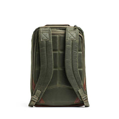 The GR1 USA - Heritage Waxed Canvas backpack in olive green is shown from the back, with padded straps, brown leather accents, and classic waxed canvas rucksack styling.