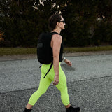 Woman rucking outdoors in neon yellow cropped leggings and black backpack GORUCK gear