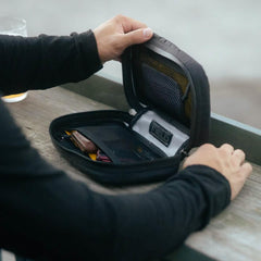 Person opening black GORUCK Field pouch with organized mesh compartments on wooden surface