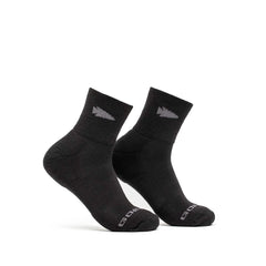 A pair of black Merino Challenge Socks - Trail Cuff by GORUCK features a small triangular logo near the cuff and branding text on the toes. Made in the USA, these ankle-length socks stand upright against a plain white background.