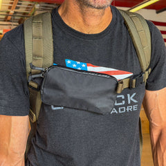Man wearing a black t-shirt and backpack with the Sternum / Belt Pouch - Waterproof X-PAC attached to his chest strap for easy-access storage.