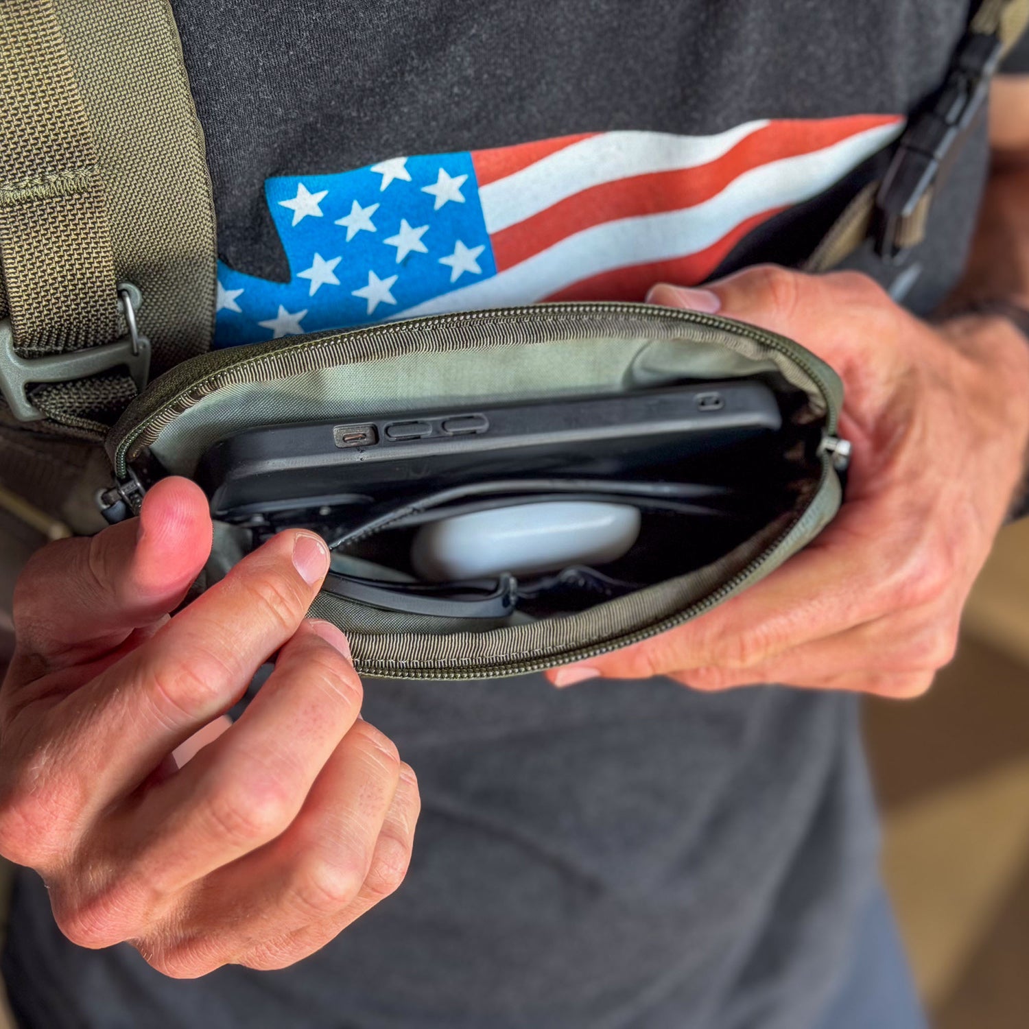 A person opens the Sternum / Belt Pouch - Waterproof X-PAC, revealing a device and earbuds case inside—ideal for hands-free, secure storage during any adventure.