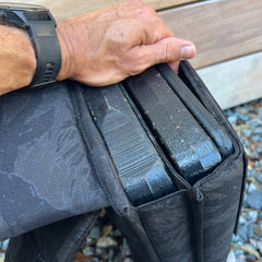 A hand holds a black carrying case with two thick black metal plates, perfect for rucking workouts or use with the Ruck Plate Carrier 3.0.