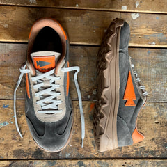 Two Mackall 45 Fog sneakers in gray, brown, and orange with arrow logos shown on a worn wooden surface.