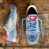 A pair of Mackall 45 Americana sneakers in blue with white and red accents displayed on a worn wooden surface.