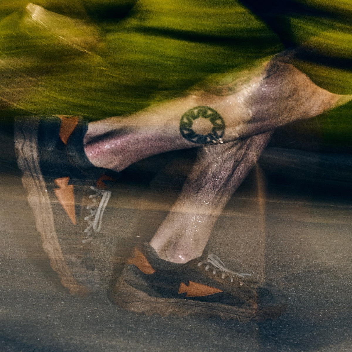 Motion-blurred legs of a runner wearing dark sneakers with orange arrow accents during an Austin rucking event.