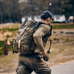 A person covered in mud carrying a muddy backpack runs along a path wearing abrasion-resistant, fast-drying pants.