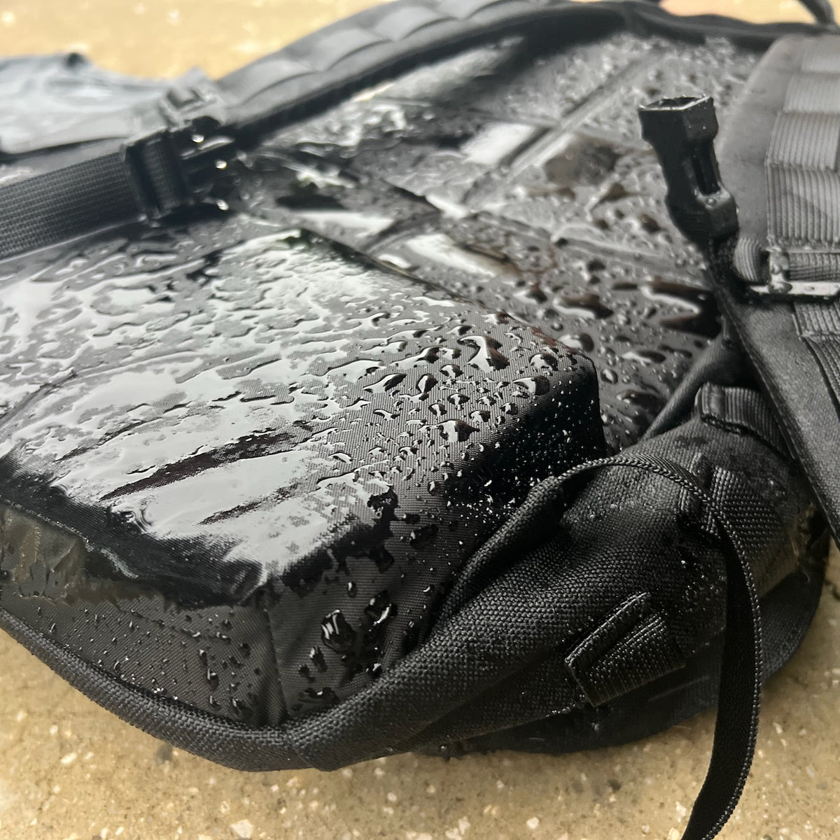 A black tactical-style backpack for distance rucking covered in water droplets.
