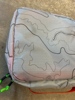 Close-up of the Ripstop Robic XL Packing Cube in gray with black contour lines and green zipper pulls, ideal for travel organization, displayed on a textured surface.