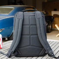 GORUCK rucksack with padded straps on a wooden table, blue classic car in background