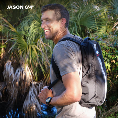 A man with a backpack smiles outdoors near greenery, carrying his Basic Rucker®; text “JASON 6'4” appears in the top left corner.