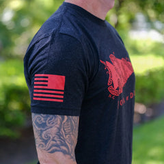 Person wearing black GORUCK t-shirt with red Join or Die graphic and red flag design on sleeve, outdoor setting