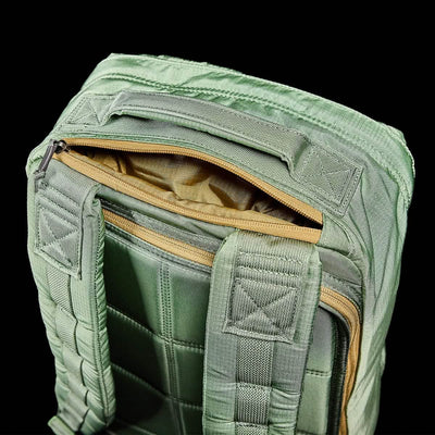 Close-up of a GR1 USA - Ripstop ROBIC® rucksack by GORUCK in green against a black background. The top zipper compartment is open, showcasing its tan interior. This water-resistant bag boasts cushioned straps and reinforced stitching with a quilted texture.