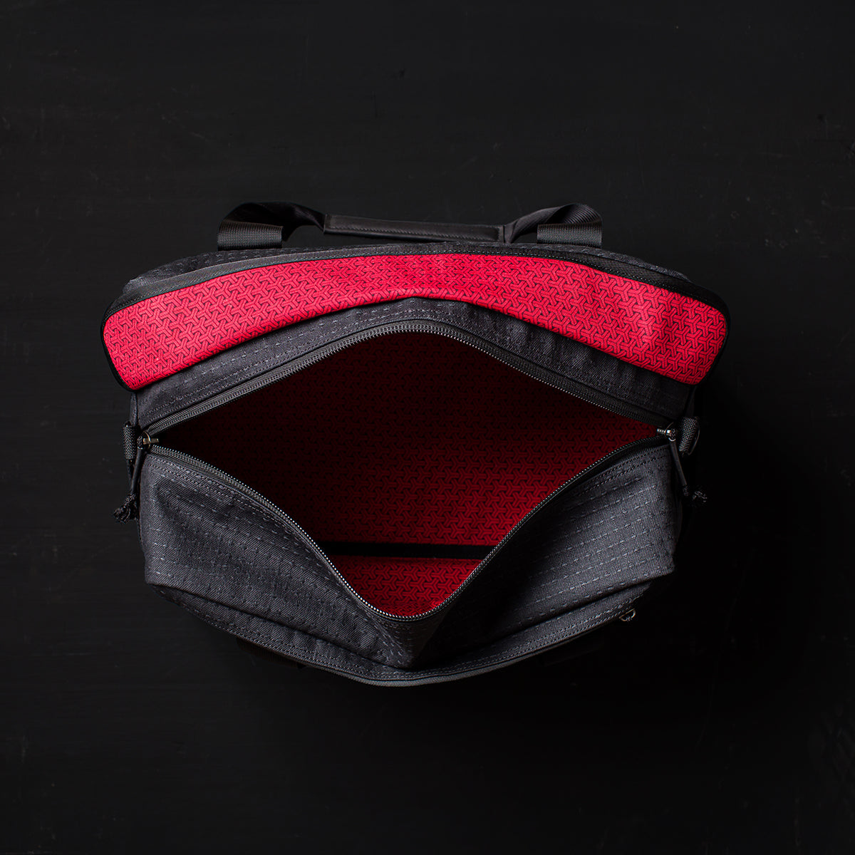 The Kit Bag x Carryology - GRXC2 Samurai 2.0 is shown open from above, revealing its red patterned interior and custom technical fabric, set against a dark background.