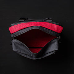 Open black GORUCK kitbag with red patterned interior lining on dark background
