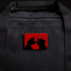Black GORUCK bag with red and black patch featuring two samurai warriors in combat silhouette