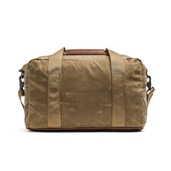 The Kit Bag - Waxed Canvas is a brown canvas duffel inspired by classic pilot flight bags, featuring tan handles and a detachable shoulder strap, displayed on a white background.