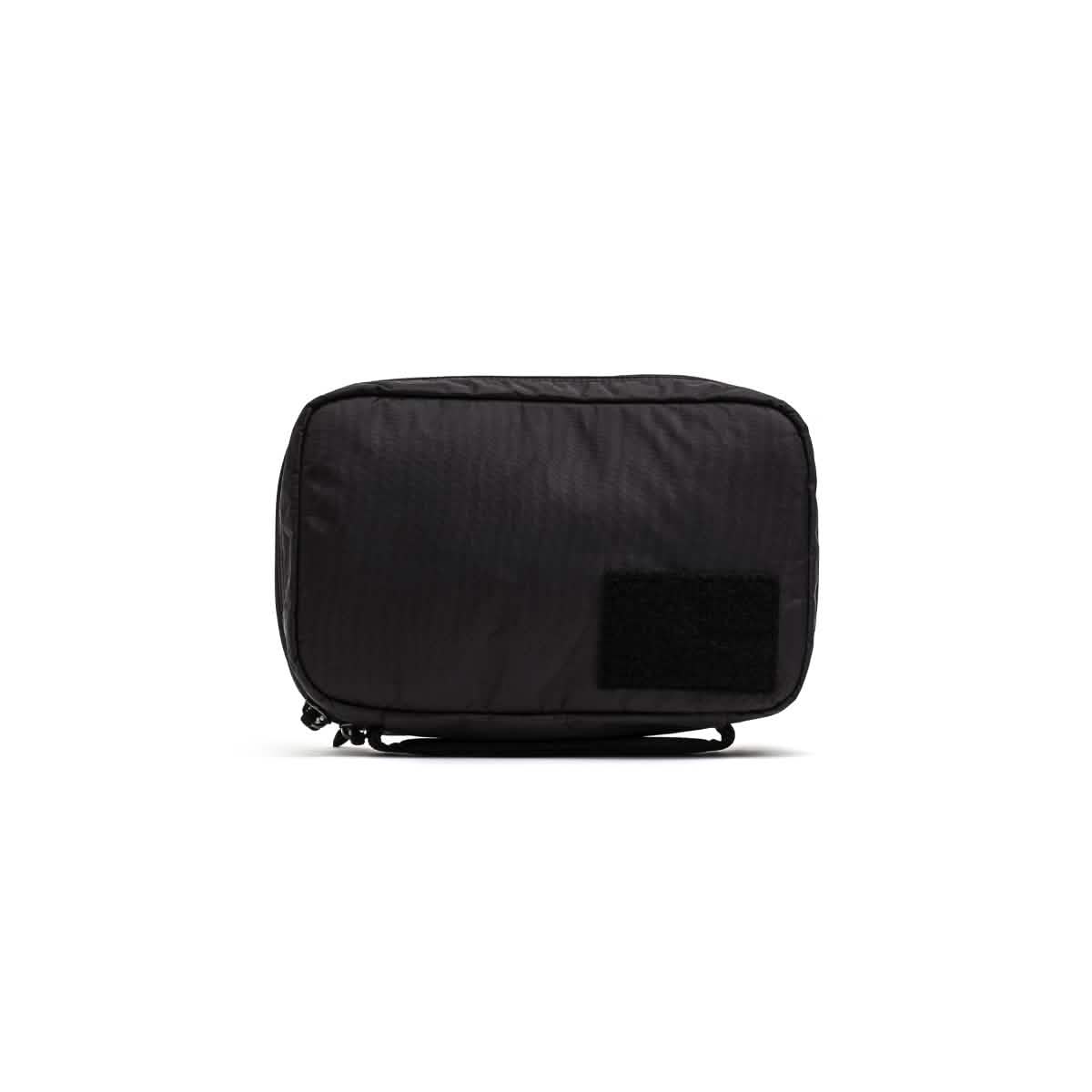 The GR1 Field Pocket - Dyneema by GORUCK is a black rectangular electronics organizer crafted from durable Dyneema material. Its minimalistic design is accented by a small Velcro patch on the lower right corner, making it an excellent travel accessory. The straightforward aesthetic stands out beautifully against a plain white background.
