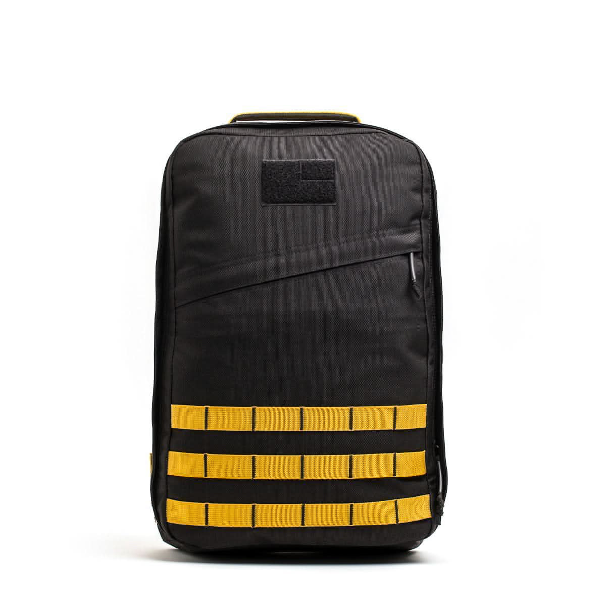 The GR1 USA - Cordura is a black rucksack backpack featuring yellow horizontal straps and a small black patch on the upper front, shown against a white background. Inspired by Special Forces backpack design.