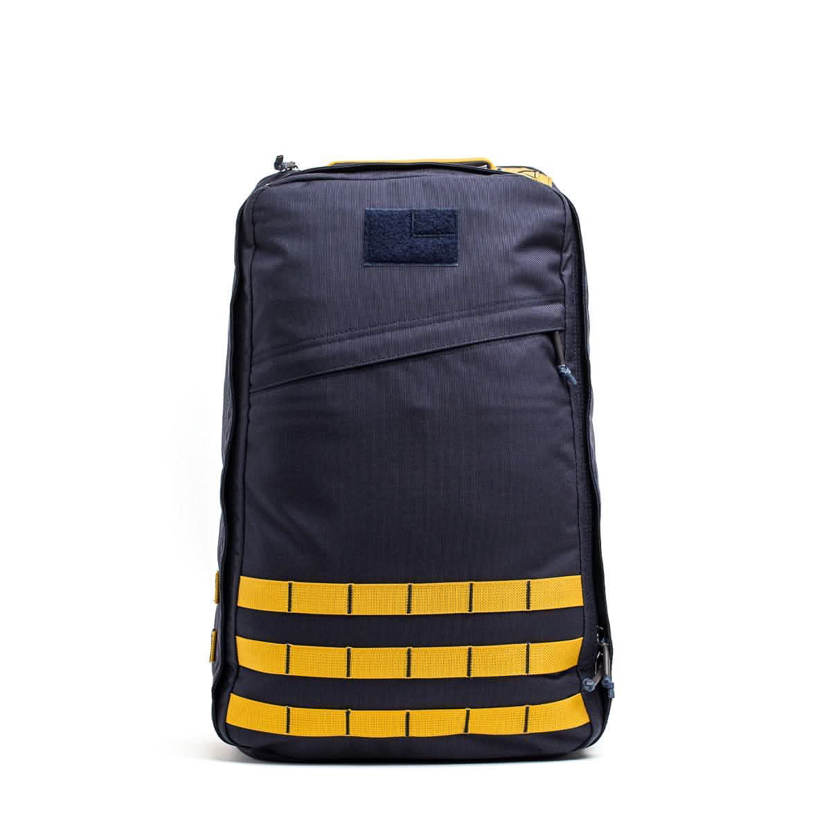 The GR1 USA - Cordura is a navy blue everyday carry backpack with yellow straps and a diagonal front zipper, inspired by Special Forces grade designs, shown standing upright against a white background.