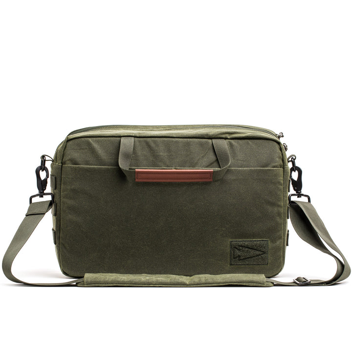 The GORUCK Shoulder Bag - Waxed Canvas boasts a rugged green canvas treated with a Martexin Wax finish. It features a front flap, strong handles, and an adjustable strap for comfortable asymmetrical carrying.