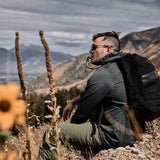 Man in GORUCK ToughMesh hoodie and backpack resting outdoors in the mountains