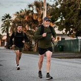 Two men rucking with GORUCK backpacks on a street, wearing athletic outdoor gear