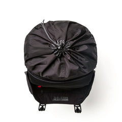 Top view of black GORUCK rucksack with drawstring closure and front buckle straps on white background