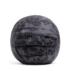 The Sand Medicine Ball features a gray camo pattern with "GORUCK" and "100" on the front, making it ideal for core stability workouts in your home gym.