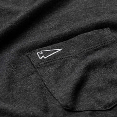 Close-up of the Men's Long Sleeve Pocket Tee - Tri-Blend in dark gray, featuring an embroidered white arrowhead design above the shirt pocket.
