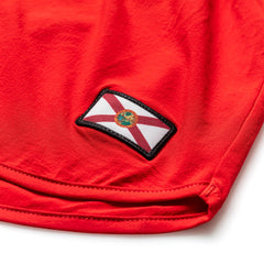 A Men’s Ranger Panties - ToughStretch patch with a red cross on white is sewn onto red PT shorts made from durable ToughStretch fabric.