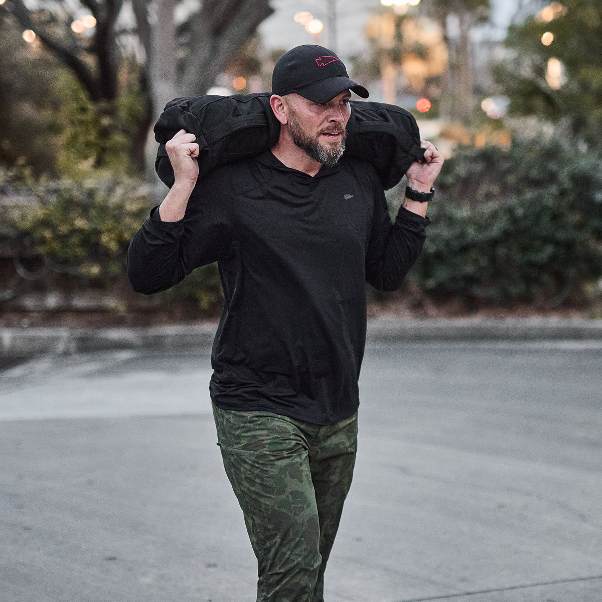 Man wearing Men's USA Sun Hoodie - ToughMesh, offering breathable performance and UPF 30+ sun protection, carrying a weighted bag outdoors.
