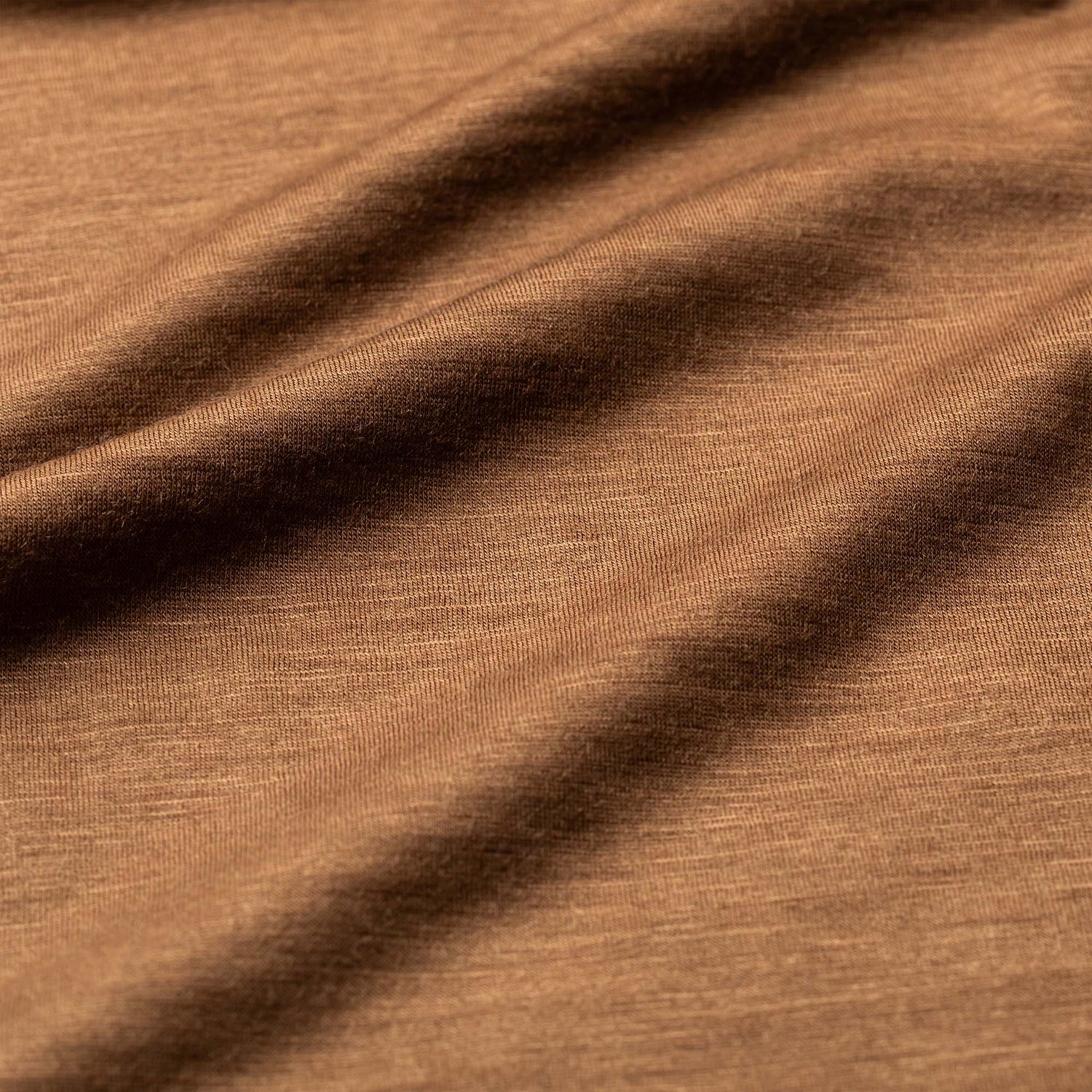 Close-up of the Men's Commando Polo in brown Merino wool, highlighting its textured fabric and soft folds that create gentle shadows.