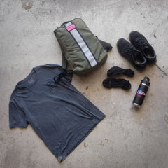 Merino Challenge Socks - Ankle (No-Show), a gray t-shirt, backpack, black shoes, and a water bottle arranged on a concrete floor.