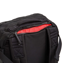 Close-up of black GORUCK Mesh Ruck backpack with red interior lining and durable zippers on white background